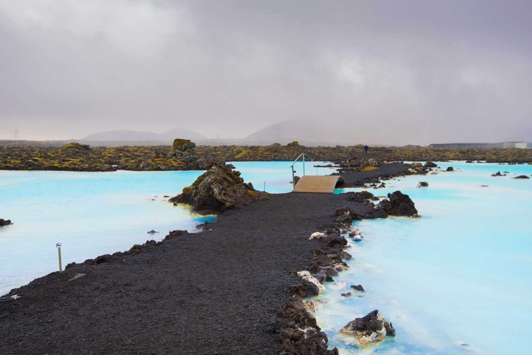 The blue water between the lava stones covered with moss just outside the Blue Lagoon resort of Iceland